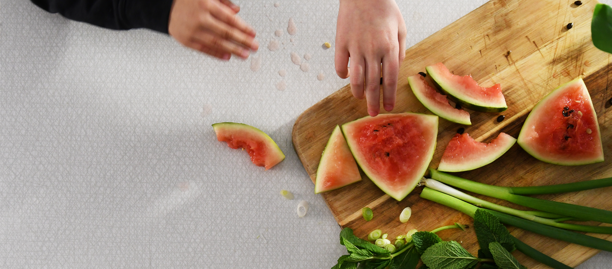Barnhänder som stäcker sig efter skivor av vattenmelon